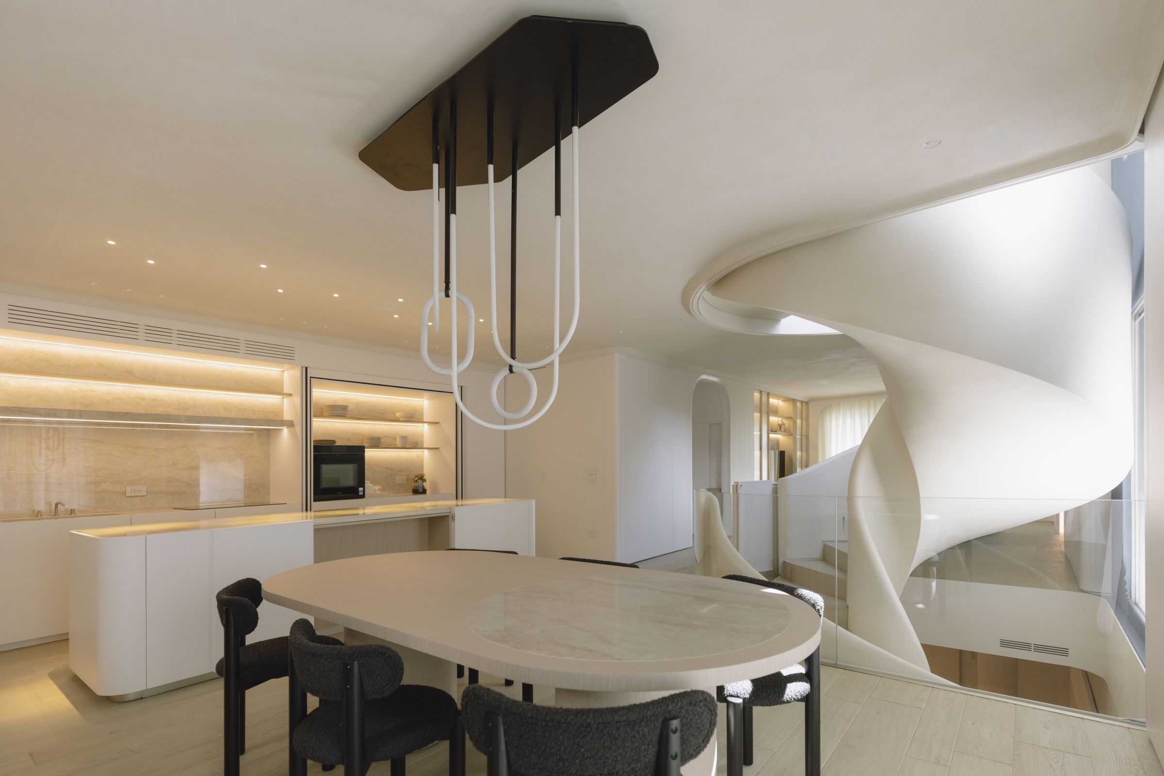 White helical staircase beside the dining table and the kitchen with lit shelves, Apulian D.F. project